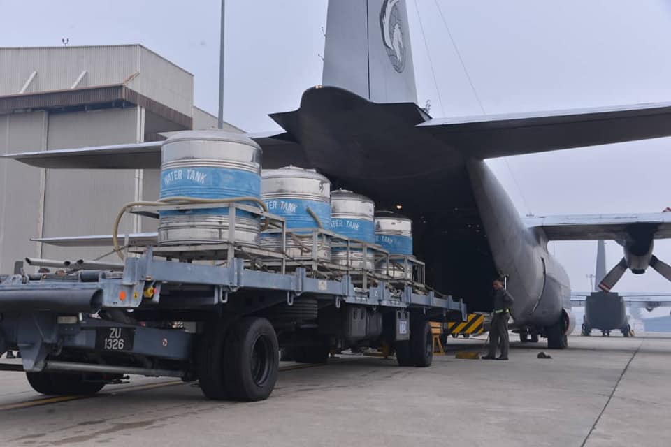 Vier tanks met een mengsel van zout en water worden op de Lockheed C-130 Hercules-transporter van RMAF geladen.