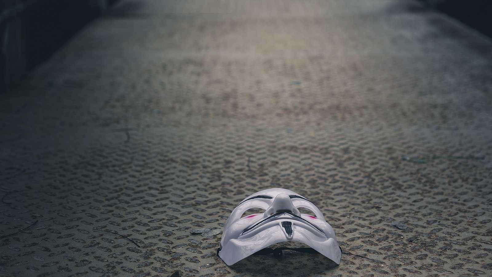 Een man vervalst een masker op de vloer van een catwalk.