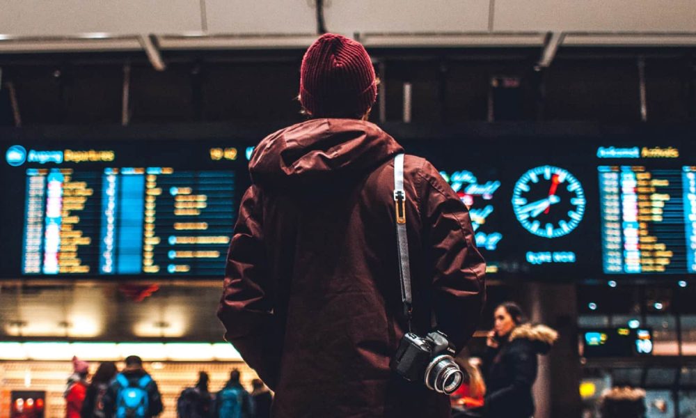 man standing at airport looking at travel directions