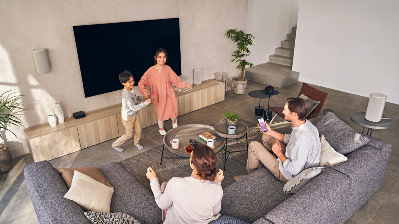 configuración de altavoces inalámbricos sony ht-a9 en una sala de estar con una familia escuchando música