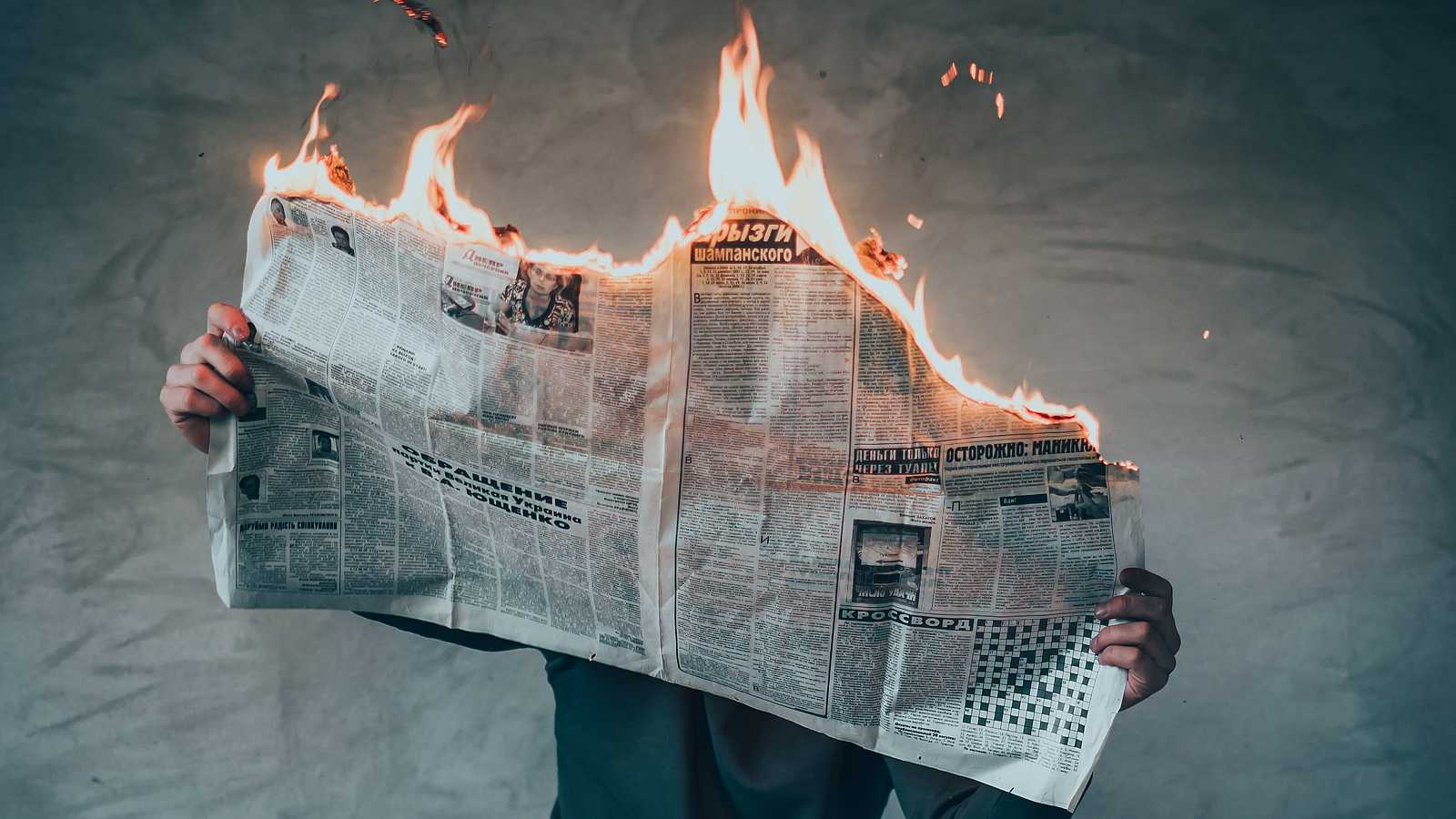 persona leyendo un periódico en llamas